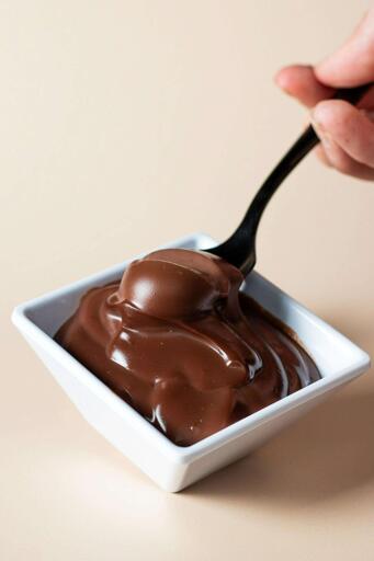 a hand scooping up a bit of melted chocolate with a spoon