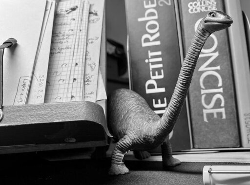 B&W picture of a toy dinosaur on my desk, in front of some books.