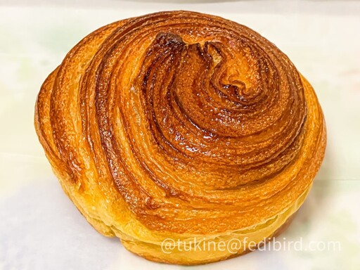 焼き色が美しい渦巻き状のパンが白い紙の上に置かれている。